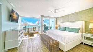 A hotel room with a large bed, a balcony with a view, a ceiling fan, and a television. - LaPlaya 205D! Spectacular views! (Longboat Key)