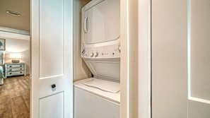 Une buanderie équipée d’un lave-linge et d’un sèche-linge, une porte avec une poignée et une table de chevet avec une lampe.