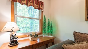 Un bureau en bois, une lampe, une figurine d’ours, une bougie et une petite décoration en forme d’arbre.
