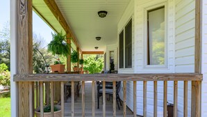 Une véranda en bois avec une balustrade, des plantes en pot et du mobilier d’extérieur.