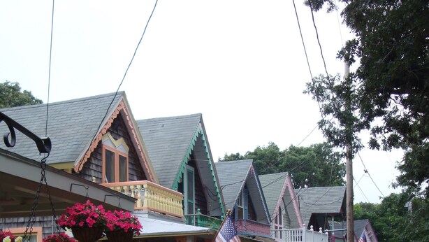 A row of traditional houses with front porches, American flags, and flower gardens. - Quaint Studio near Mashpee Commons (East Falmouth)