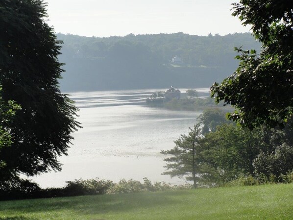 A serene lake with a house on the shore, surrounded by dense trees.