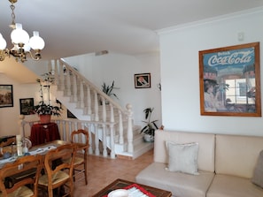 A living room with a staircase, a dining area, and a sofa.