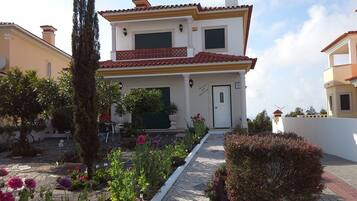 Stunning two-story residence with a central entrance, surrounded by a beautifully maintained garden and a tall tree.
