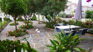 A patio with stone flooring, a table, chairs, and potted plants. - Villa for rent in Nazaré Portugal (Nazaré)