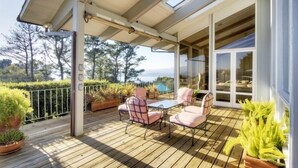 A covered outdoor deck with a table and chairs, surrounded by potted plants and overlooking a scenic view. - Luxury, San Francisco Bay Area (Tiburon): 5000 sq. ft., 4 bed, 5 bath (Tiburon)