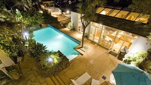 A swimming pool surrounded by stone steps and potted plants, with a patio area featuring white lounge chairs and a blue umbrella. - Luxury, San Francisco Bay Area (Tiburon): 5000 sq. ft., 4 bed, 5 bath (Tiburon)