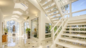 A spacious, modern interior with a central staircase, large windows, and a polished floor. - Luxury, San Francisco Bay Area (Tiburon): 5000 sq. ft., 4 bed, 5 bath (Tiburon)