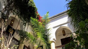 A courtyard with a white building, arched windows, and a metal railing. - Gorgeous Award Winning Riad in Marrakech Medina (Marrakech)