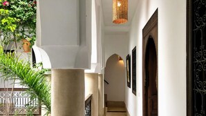 A corridor with a white wall, a wooden door, and a metal gate. - Gorgeous Award Winning Riad in Marrakech Medina (Marrakech)