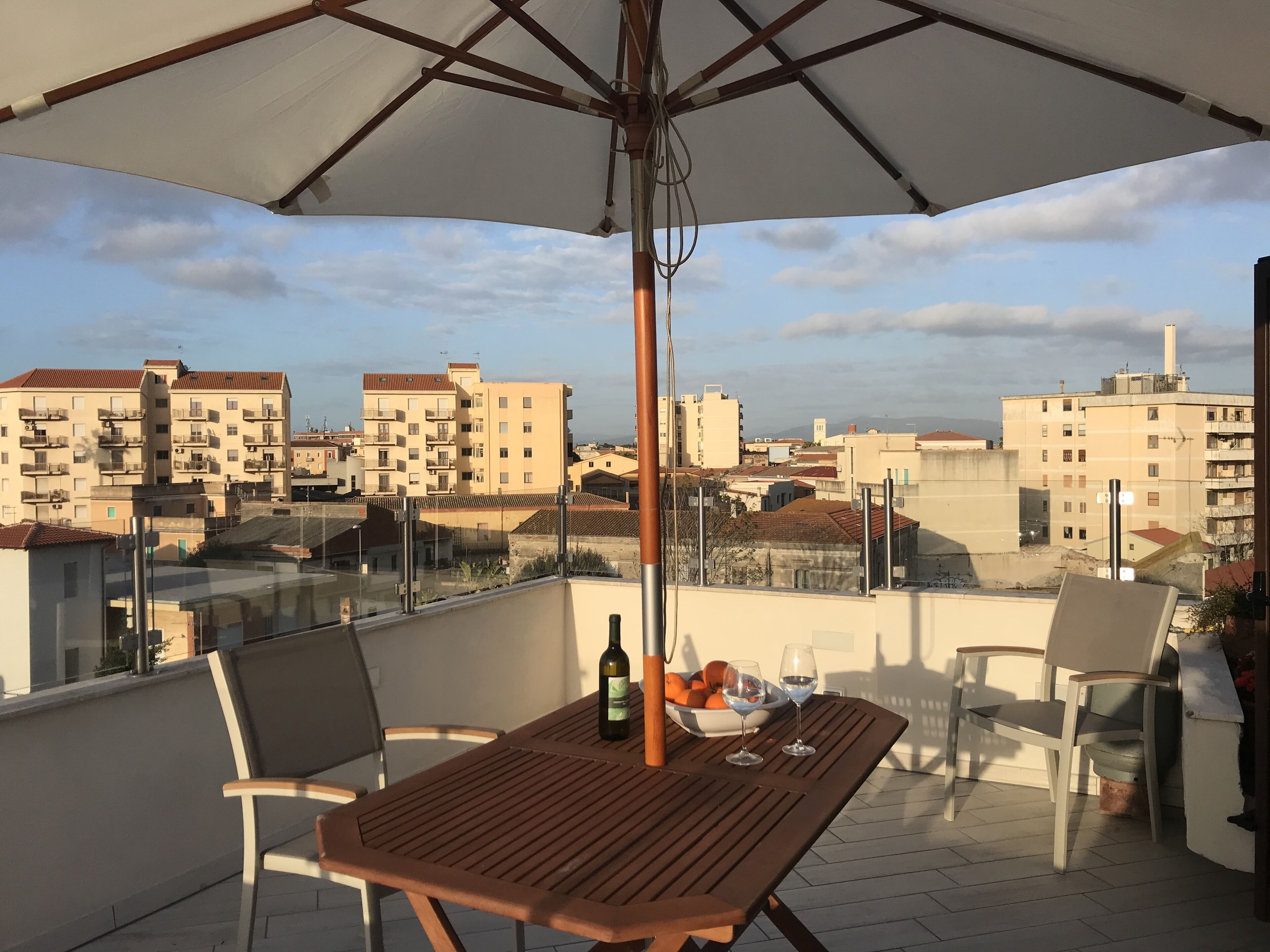 Een terras op het dak met een tafel, stoelen en een parasol.