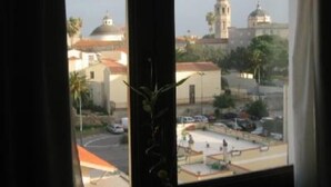 Une vue depuis une fenêtre donnant sur un paysage urbain, avec des immeubles et un parking.