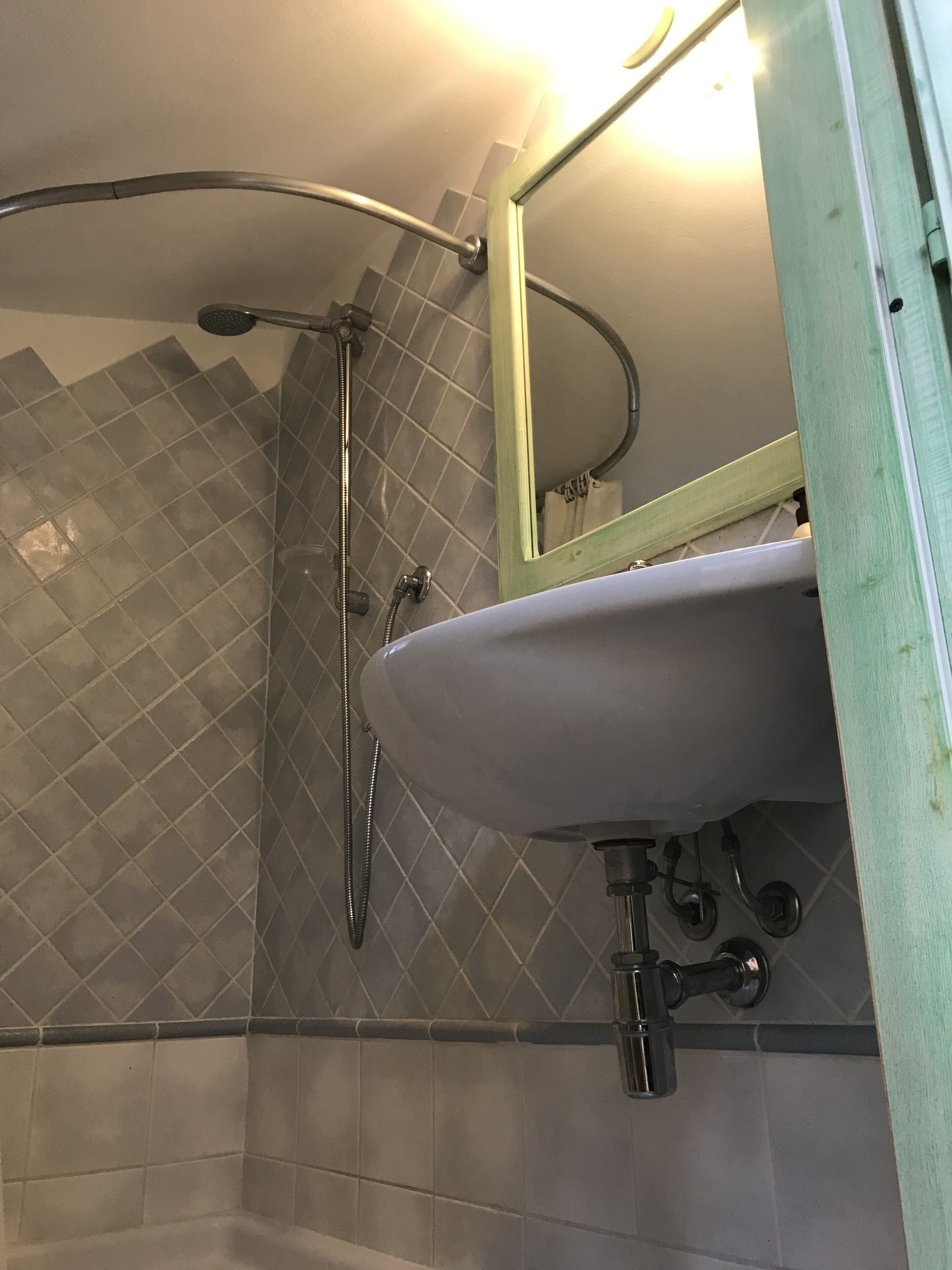 A bathroom with a shower, a sink, and a mirror.