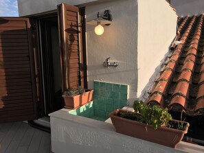 Enjoy the serene outdoor space with a wooden door, wall-mounted light, and lush greenery.