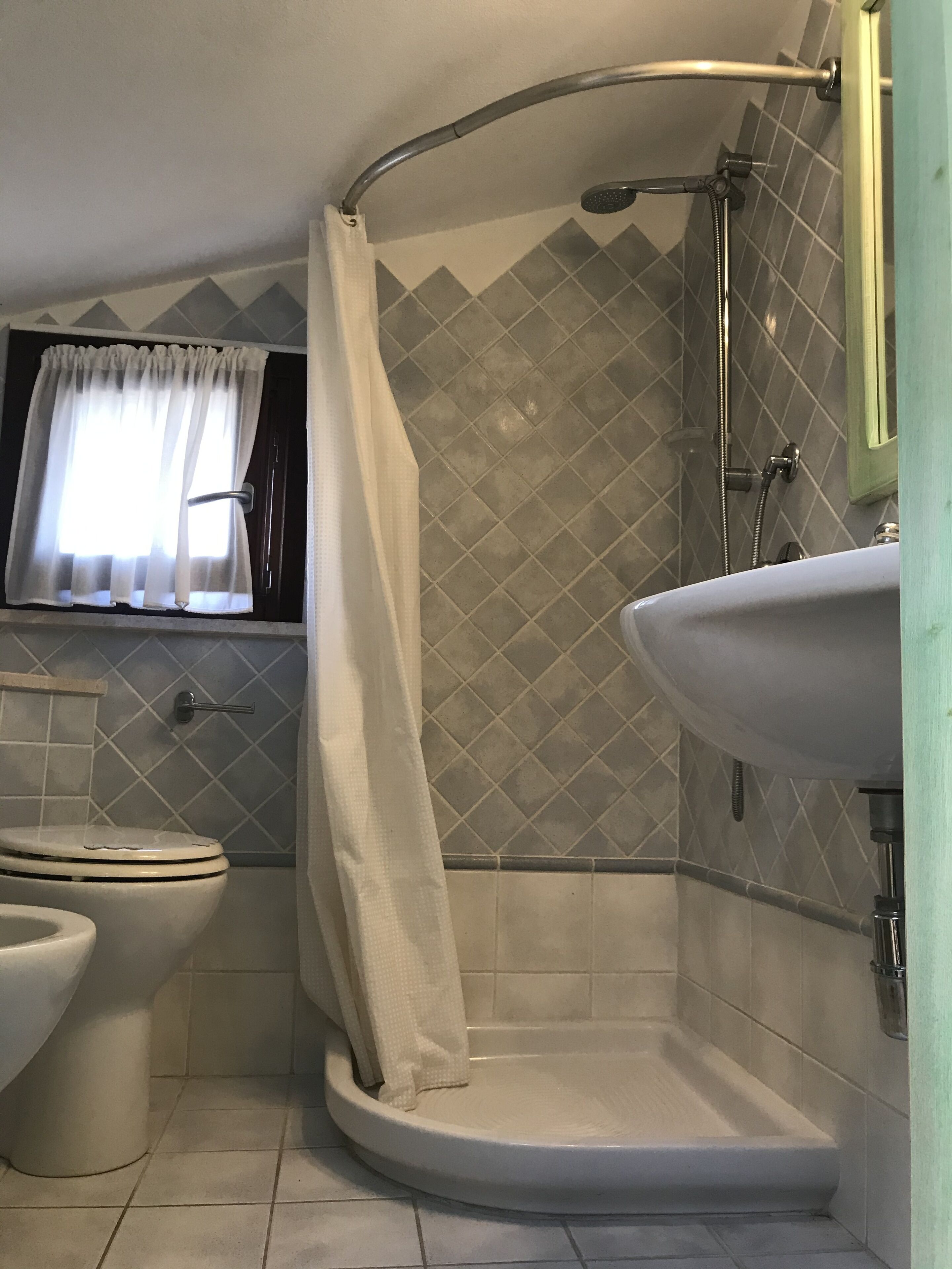 Et badeværelse med brusebad, toilet og håndvask.