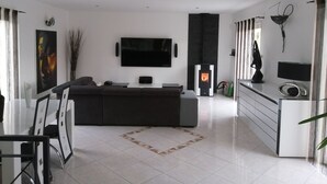 A modern living room with a black sofa, a flat-screen TV, and a fireplace.