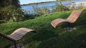 A lakeside bench area with a view of a calm lake and distant buildings. - Original holiday in the westcoast STORE in Friedrichstadt / North Sea for 2-4 P.  (Friedrichstadt)