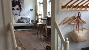 A wooden staircase leading to a dining area with a table and chairs, a hanging basket, and a painting on the wall. - Original holiday in the westcoast STORE in Friedrichstadt / North Sea for 2-4 P.  (Friedrichstadt)