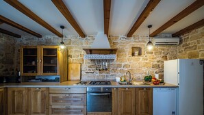 Una cocina rústica con paredes de piedra, armarios de madera, una estufa a gas y un refrigerador blanco.