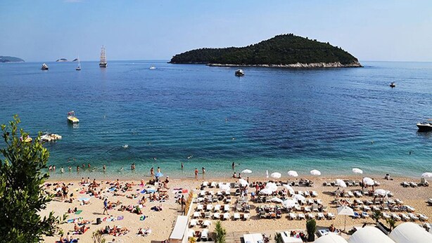 A beach with numerous sun loungers and umbrellas, a small island in the background, and several boats on the water. - Ankora 1 with terrace and great view next to Old Town with HotTub in the garden (Dubrovnik)