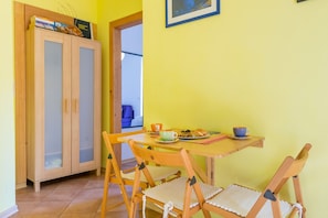 Uma sala de jantar com uma mesa e cadeiras de madeira, um armário com livros e um quadro na parede.
