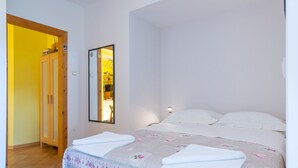 A bedroom with a bed, a mirror, and a wooden wardrobe. - Ankora 1 with terrace and great view next to Old Town with HotTub in the garden (Dubrovnik)