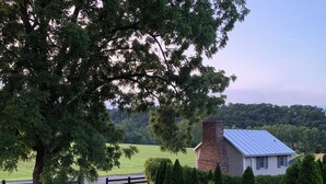 Une maison avec une cheminée en briques, entourée d’une pelouse bien entretenue et d’un grand arbre.