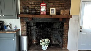 Une cheminée avec un manteau en briques, une poubelle et un vase de fleurs.