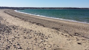 A beach with pebbles and sand, a clear blue sky, and a calm sea. - Water View 1 mi from Oak Bluffs 10 min Walk to Beach (Oak Bluffs)