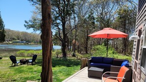 A deck with outdoor furniture, a red umbrella, and a view of a lake. - Water View 1 mi from Oak Bluffs 10 min Walk to Beach (Oak Bluffs)