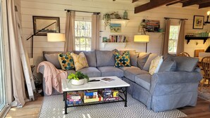 A cozy living room with a grey sectional sofa, a coffee table with a plant, and a patterned rug. - Water View 1 mi from Oak Bluffs 10 min Walk to Beach (Oak Bluffs)