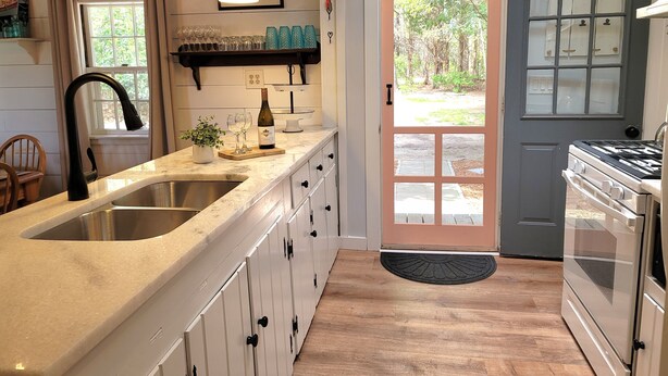 A kitchen with a sink, countertop, cabinets, a stove, and a door leading outside. - Water View 1 mi from Oak Bluffs 10 min Walk to Beach (Oak Bluffs)