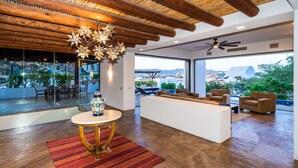 Ein modernes Wohnzimmer mit Holzboden, einer dekorativen, sternförmigen Leuchte, einem weißen Sofa und Blick auf die Stadt durch große Fenster.