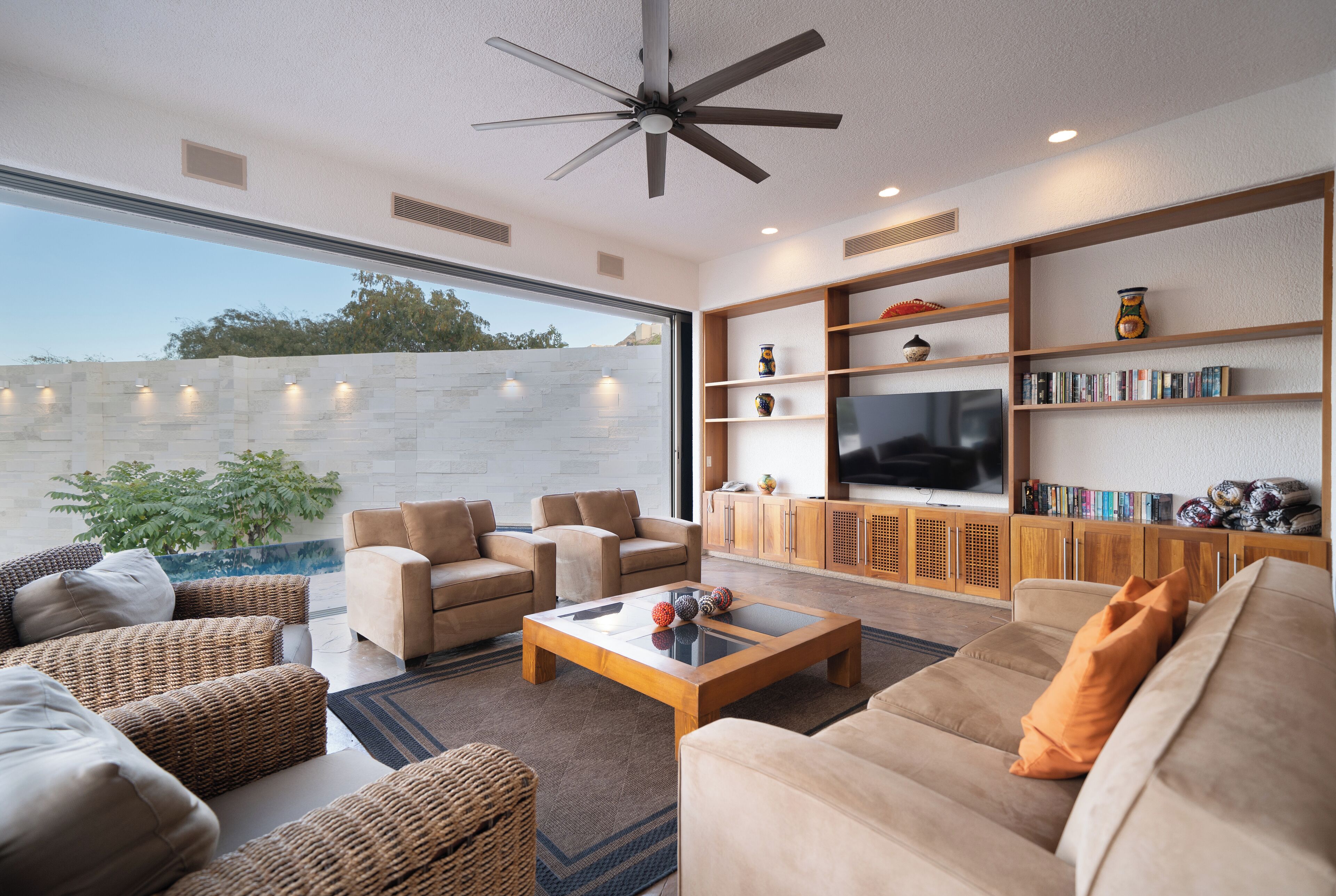 A modern living room with a large TV, comfortable seating, and a bookshelf.