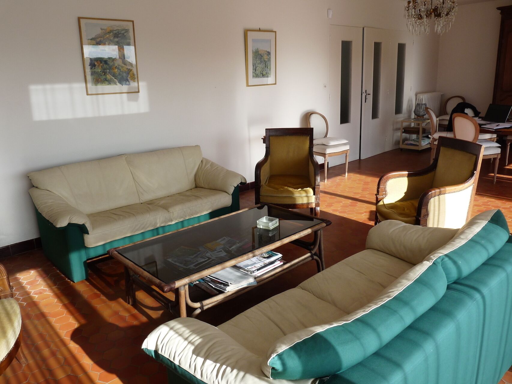 A living room with a sofa, armchairs, a coffee table, and a chandelier.