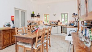 A kitchen with wooden furniture, a dining table, and a white countertop.