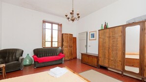A room with two sofas, a wooden cabinet, a large mirror, and a chandelier.