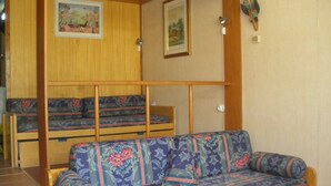 Una habitación con una cama litera de madera y un sofá tapizado con motivos florales.