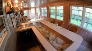 A kitchen with a long island, a refrigerator, and a dining area with chairs. - Nice Wooden House, a few steps from the beach - sleeps 6 - Strategic location (Green Turttle)