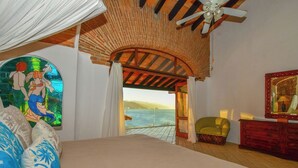 A bedroom with a bed, a chair, a dresser, and a view of the sea. - Luxury 3-bed Villa,Spectacular Views, Saline pool & Staff   (Puerto Vallarta)