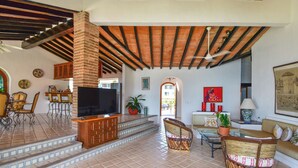 A spacious living area with a TV, wicker furniture, and a tiled floor. - Luxury 3-bed Villa,Spectacular Views, Saline pool & Staff   (Puerto Vallarta)