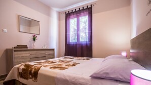 Une chambre à coucher avec un lit, une commode, un miroir et une fenêtre avec des rideaux.