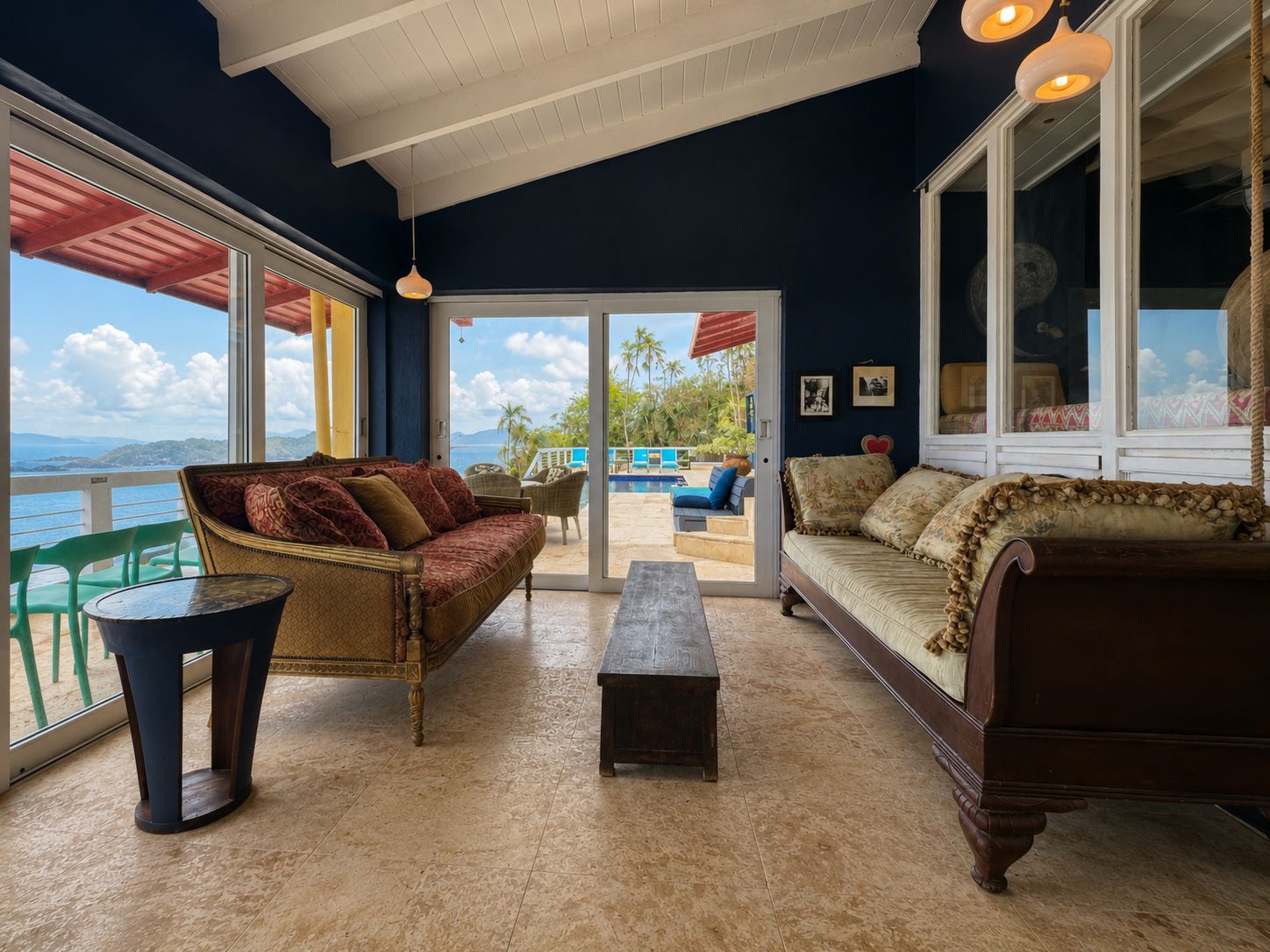 A room with a view of the sea, furnished with a sofa, a bench, and a table.