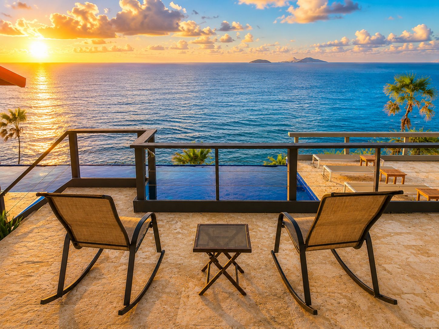 Une terrasse avec deux fauteuils à bascule et une petite table, d’où l’on peut admirer un plan d’eau et des palmiers.