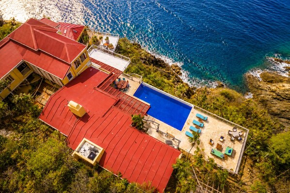 Una propietat costanera amb piscina, edificis amb teulades vermelles i vistes a l'oceà.