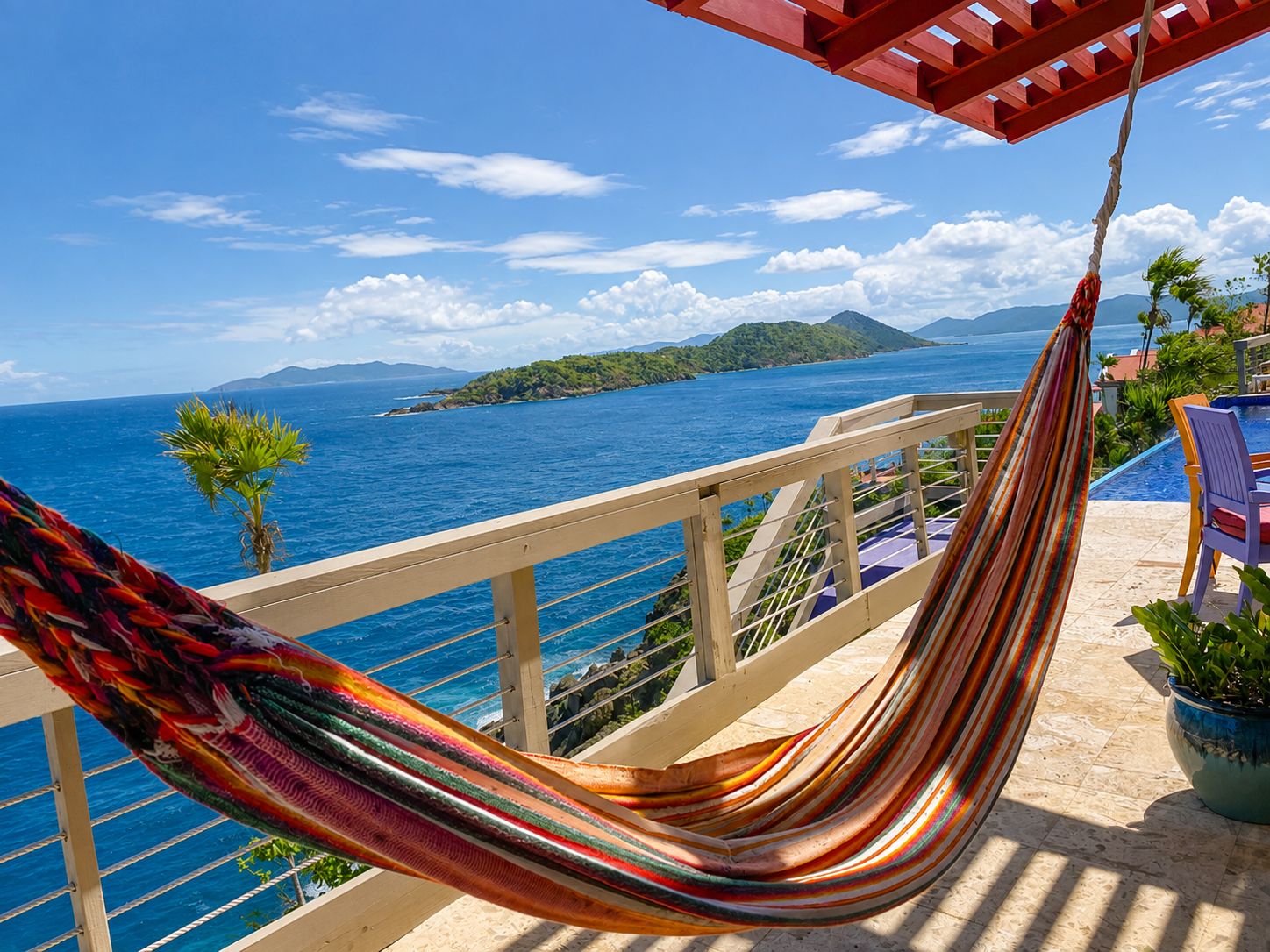 Un hamac sur un balcon donnant sur une étendue d’eau, avec une île visible au loin.