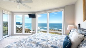 Ein Schlafzimmer mit Bett, Deckenventilator, Fernseher und Blick auf den Ozean.