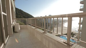 A balcony with a view of a beach and a pool. - Beautifully decorated apartment! Maulf Hill - Ocean View! 150m2 (Guarujá)