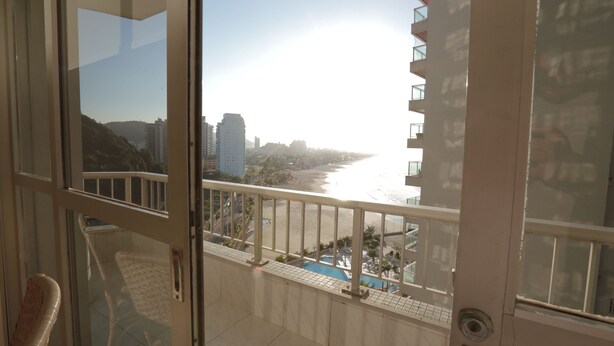 A balcony with a view of a beach and a cityscape. - Beautifully decorated apartment! Maulf Hill - Ocean View! 150m2 (Guarujá)