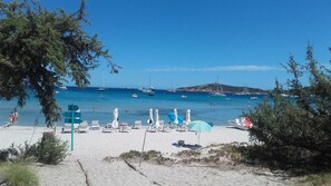A beach with white sand, clear blue water, and several boats. There are lounge chairs and umbrellas on the beach. - Villa Pinarello, 2 Minuutin Kävelymatkan Päässä Rannalta Kauniit Näkymät Lahdelle (Zonza)